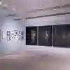 Art gallery with light blue walls displaying black-and-white portraits and sketches.